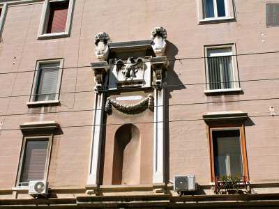 Sulla facciata che fronteggia l'antica Manifattura dei tabacchi, campeggia un�edicola celebrativa di chiara ascendenza michelangiolesca con inciso l�anno fascista di edificazione (1928). Tra le due colonne in marmo, ingrigite e sormontate dallo stemma sabaudo, regnano la scultura di un'aquila, antico simbolo romano ripreso dal regime in molte costruzioni, e una nicchia vuota che quasi sicuramente in origine ospitava un fascio littorio